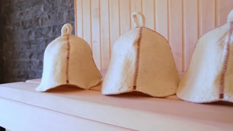 Close-up woolen hats for baths and saunas lie on a wooden bench in the steam Stock Footage 221997989