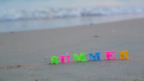 Close-up word "SUMMER" from plastic colored letters standing on sandy shore Video stock 93110562