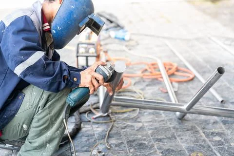 Close-up of the worker in action, kneeling on a tiled surface surrounded by.. Stock Photos