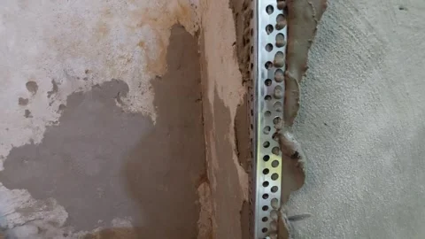 Close-up of a worker applying plaster over a metal corner bead profile on a wall Stock Footage 337053508