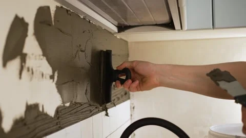 Close-up of worker applying tile adhesive mortar to a wall using a notched Stock Footage 344549312