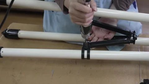 Close-up of worker attaching black tube ring clamp bracket to white telescope Stockbeeldmateriaal 334964525
