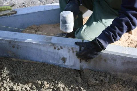 Close-up of a worker banging a hammer on a cement block, road construction. Stock Photos