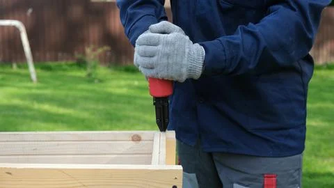 Close-up of worker in blue uniform and safety gloves using a red pneumatic na Stock Photos