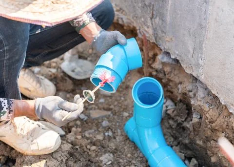 Close-up of a worker bonding plastic water pipes with adhesive at a constru.. Stock Photos