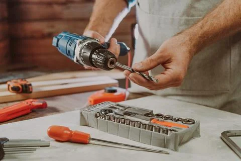Close up of worker changing a drill for screwdriver Stock Photos