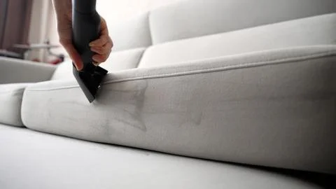 Close up of worker cleaning dirty light grey sofa with professional wet vacuum Stock Photos