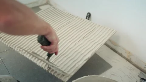 Close-up of a worker combing fresh tile adhesive across a floor with a notched Stock Footage 345833924