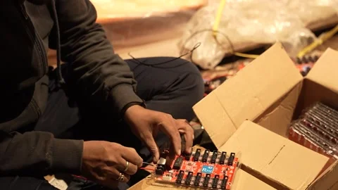 Close-up of a worker connecting wires to a red PCB. Stockbeeldmateriaal 330239651