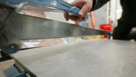 Close up of a worker cutting ceramic tile with a manual tile cutter during Stock Footage 332185459