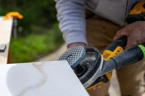 Close up of Worker is cutting a ceramic tile with an electric grinder on a Foto stock