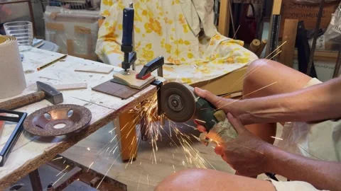 Close up of worker cutting metal piece with angle grinder tool in workshop w Stock Footage 343421545