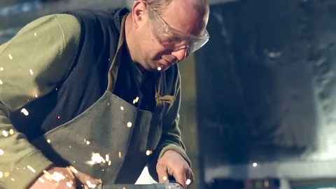 Close-up worker cutting metal. Sparks at sharpening weld Stockbeeldmateriaal 77006004