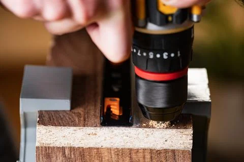 Close-up of worker drilling hole into wooden board with electric drill Stock Photos
