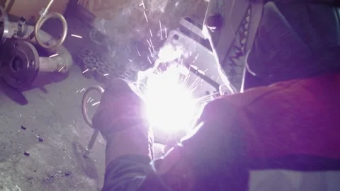 Close-up, a worker at a factory welds a pipe, sparks fly Stock Footage 157590896