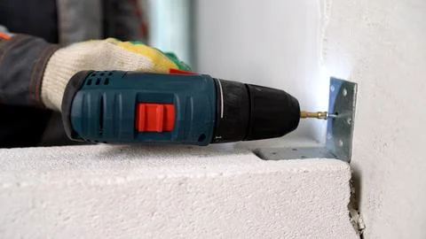 Close-up of a worker in a glove using a cordless power drill to fasten a meta Фото