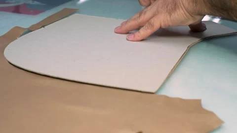 Close-Up Worker Hand Cutting Leather Pattern on Glass Table with Utility Knife Stock Footage 322057764