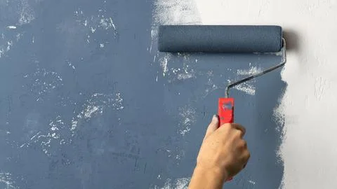 Close up of a worker hand holding paint roller. House renovation process with Stock Photos