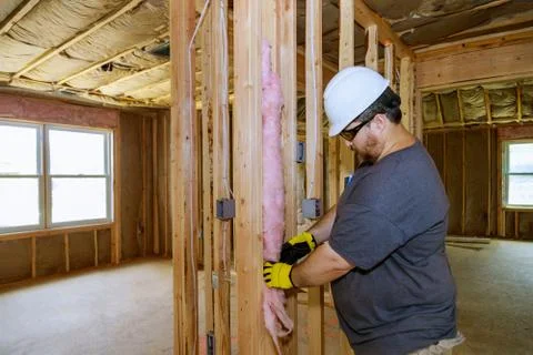 Close-up of worker hands in gloves insulating using mineral wool insulation s Stock-Fotos
