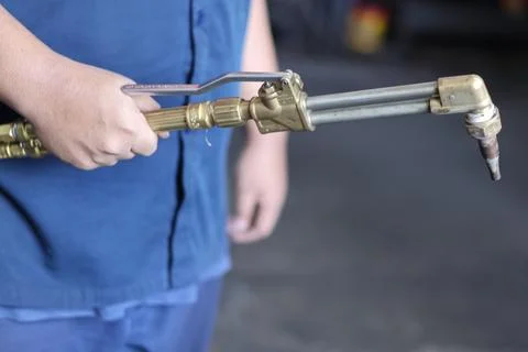 Close up of a worker holding a gas welding torch in an industrial workshop. Stock Photos