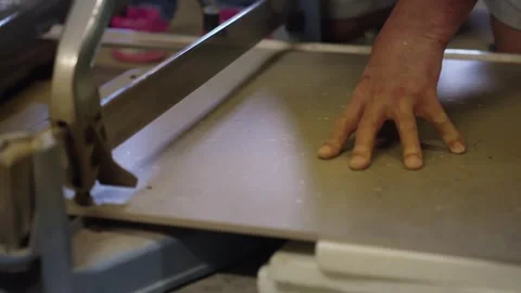 Close-up of a worker holding a large gray floor tile on a manual rail cutter Stock Footage 346260285