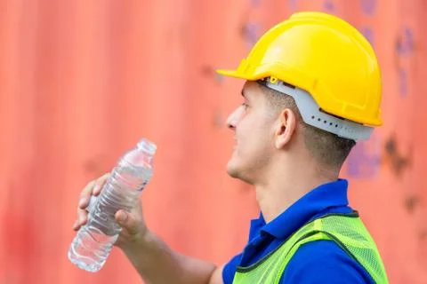 Close up of Worker man in hard hat drinking water at containers cargo 스톡 사진