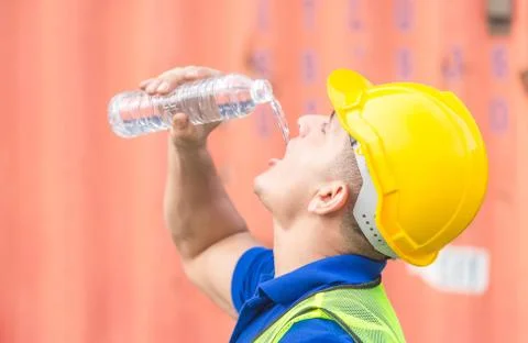 Close up of Worker man in hard hat drinking water at containers cargo Stockfoto's