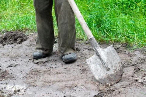 Close up of worker man legs digging soil, ground with shovel in rubber boot.. Foto stock