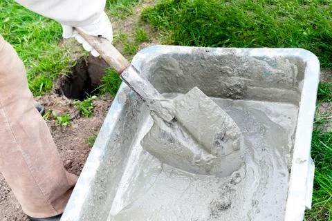 Close up worker mans hands in gloves mixing, stirring cement slurry, concre.. Stock Photos