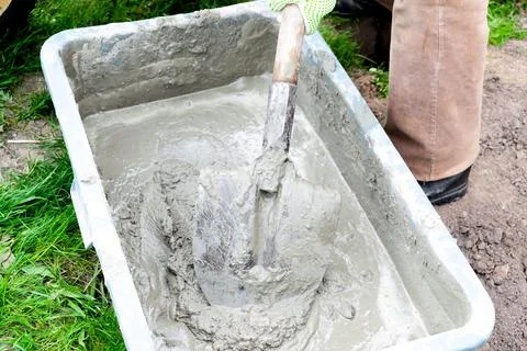 Close up worker mans hands in gloves mixing, stirring cement slurry, concrete Stock Photos
