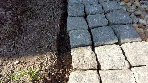 Close-up of worker placing granite paving stone in garden path Vídeos de archivo 333643042