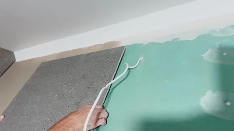 Close-up of a worker positioning a large gray wall tile over a prepared backing Video stock 345078801