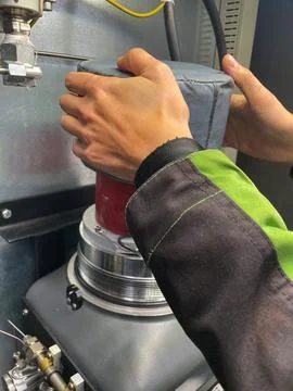 Close-up of a worker in protective gear operating industrial machinery. Stock Photos
