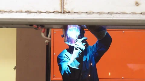 Close-up of worker in protective uniform and safety mask is welding steel Stock Footage 202048989