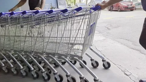 Close up of a worker pushing a row of shopping carts in a supermarket. Stock Footage 333785020