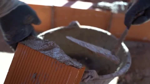 Close up of a worker putting cement on a brick and removing the excess ceme.. Video stock 242035958