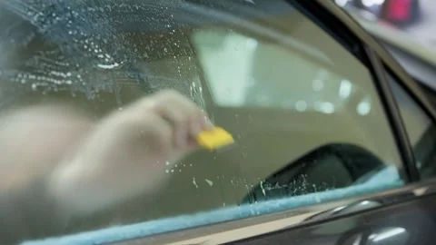 Close-up of a worker s hand removing remaining tint film and adhesive residue Video stock 337537934