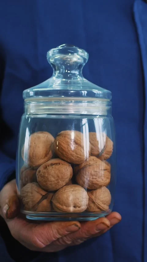 Close-up, worker s hands hold two glass jars of walnut, of different kinds, Stock Footage 323085970