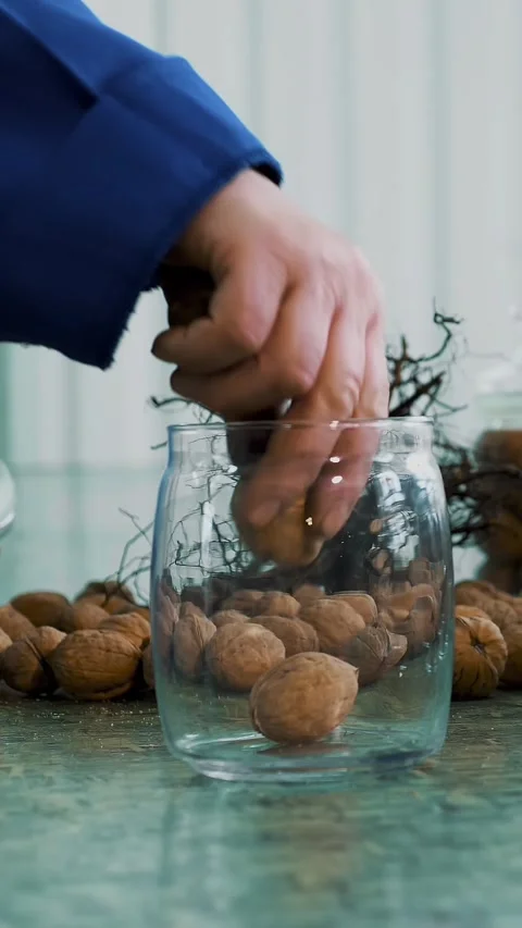 Close-up, worker s hands put walnuts in glass jars. different kinds, grown Stock Footage 323369202