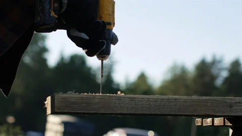 Close-up of a worker with a screwdriver twists a screw into a board outside 動画素材 111462951