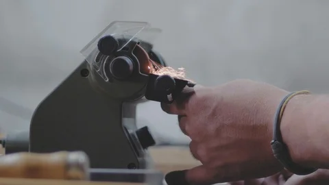 Close-up, worker sharpening a carpentry knife on a grindstone, sparks fly. 4k Stock Footage 116474854