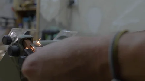 Close-up of a worker sharpening a chisel on an electric grindstone. sparks Stock Footage 116528965