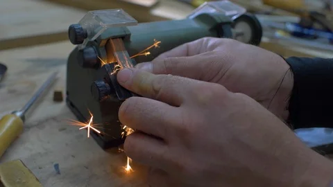 Close-up, worker sharpening a chisel on a grindstone, sparks beautifully fly Stock Footage 116711424