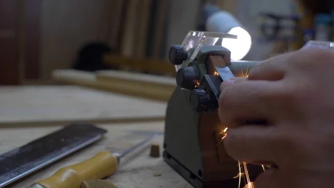 Close-up, worker sharpening a chisel on a grindstone, sparks beautifully fly Stock Footage 116711471
