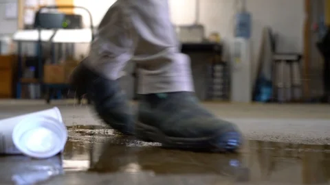 Close-up of a worker slipping on a wet floor in a warehouse or factory. Stock Footage
