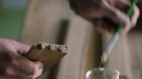Close-up. a worker smears glue with a brush on a wood piece with a dovetail j Stock Footage 144244783