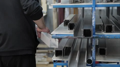 Close-up of a worker stacking finished cut aluminium profiles on a rack Stock Footage 302473360