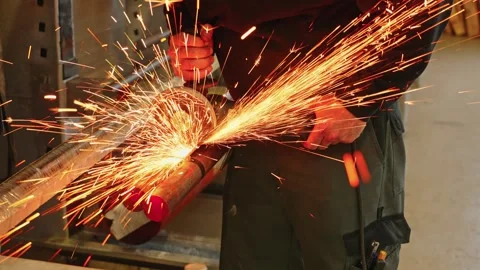 Close-up of a worker using an angle grinder to cut or grind a steel pipe Stock Footage 346791669