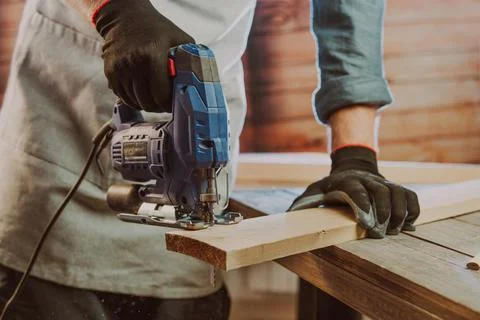 Close up of worker using electric jigsaw in the workshop Stock Photos