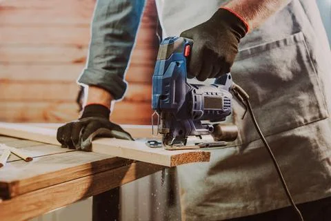 Close up of worker using electric jigsaw in the workshop Stock Photos